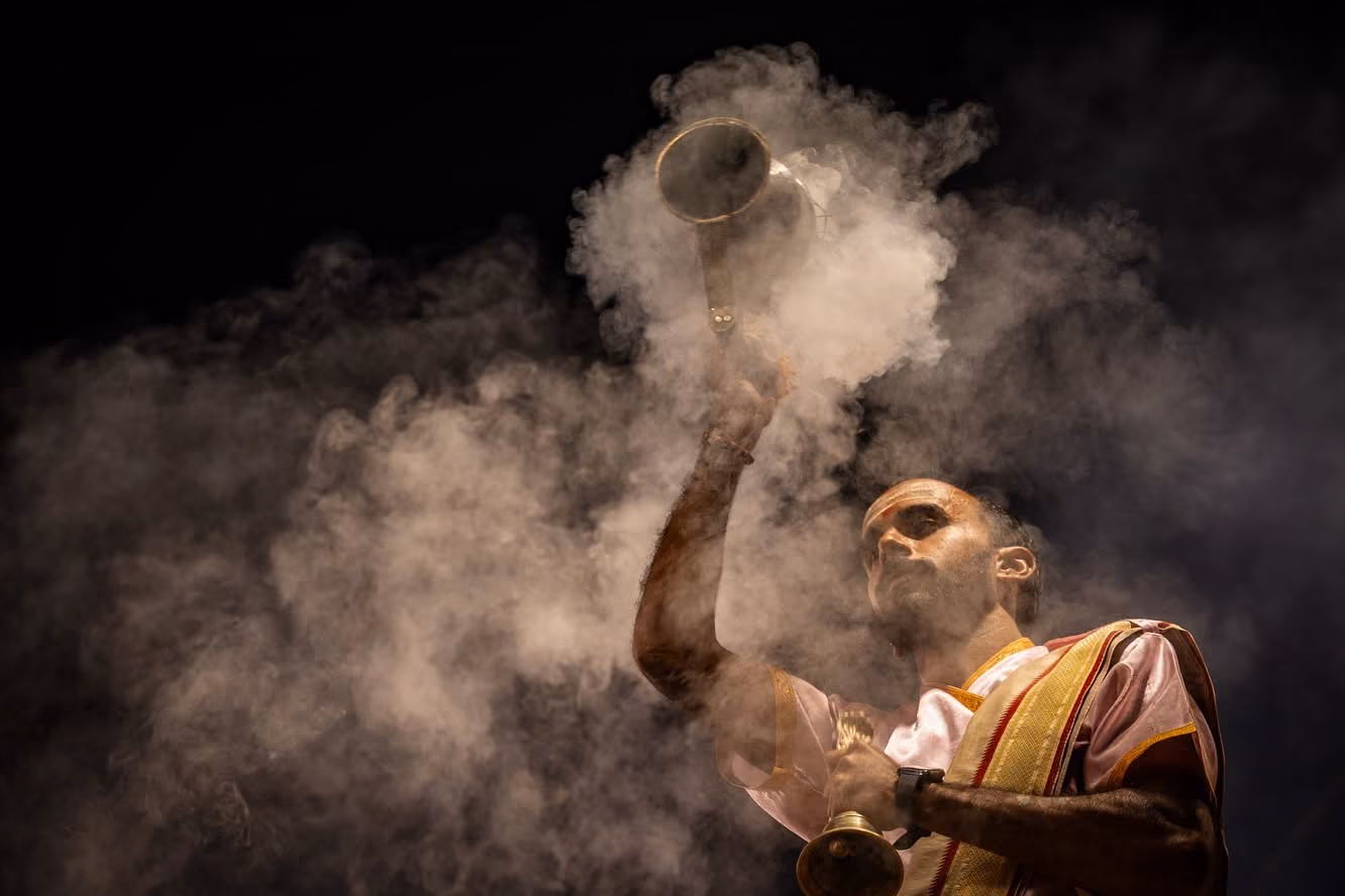 A priest performing Ganga aarti with incense smoke