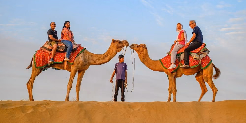 Visitors on a camel ride across sand dunes in Rajasthan