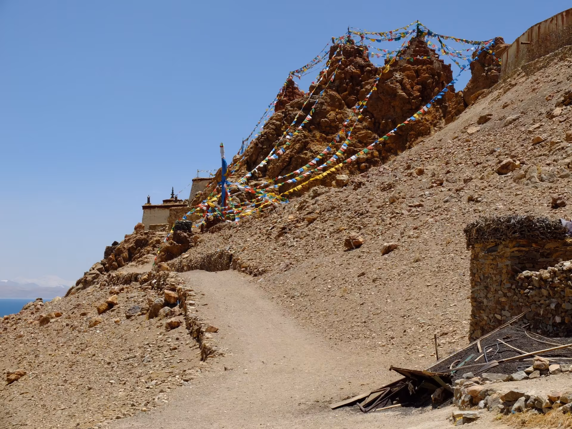 A dirt path climbing to Chiu Gompa beneath strings of prayer flags on a rocky slope